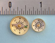 Military Special Forces Survival Button Compasses next to an inch scale